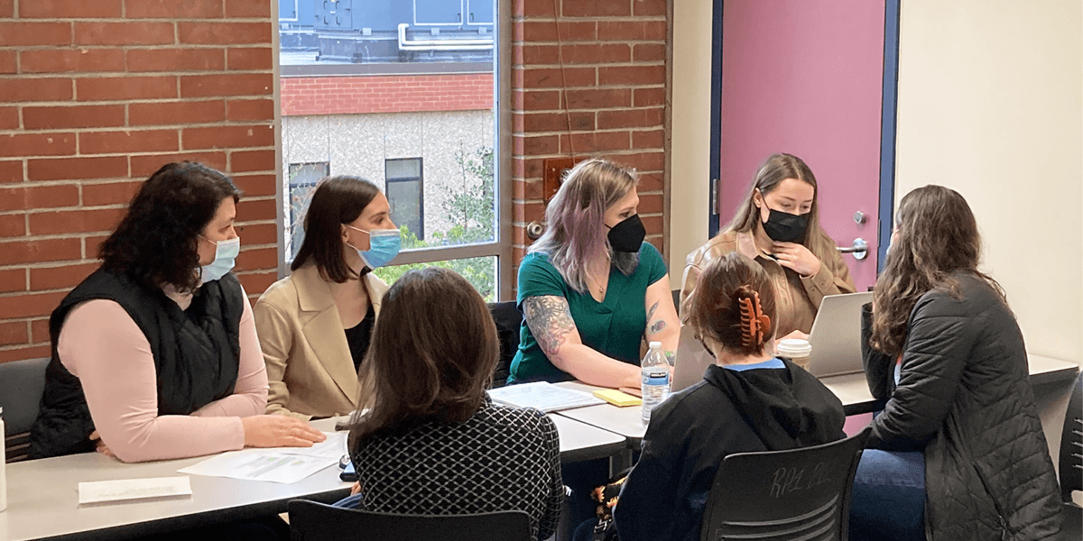 Volunteers and refugees gather at a table to work on applications.