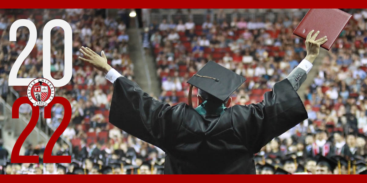 Photo of SU graduate facing an audience, holding diploma with arms outstretched.