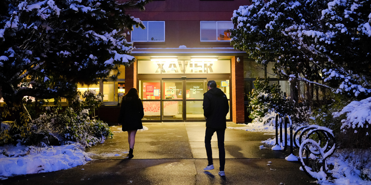 Two students walking back to Xavier Hall in the winter