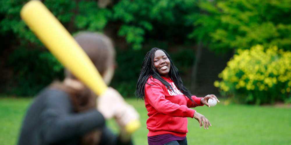   Two students play Wiffle ball on lawn