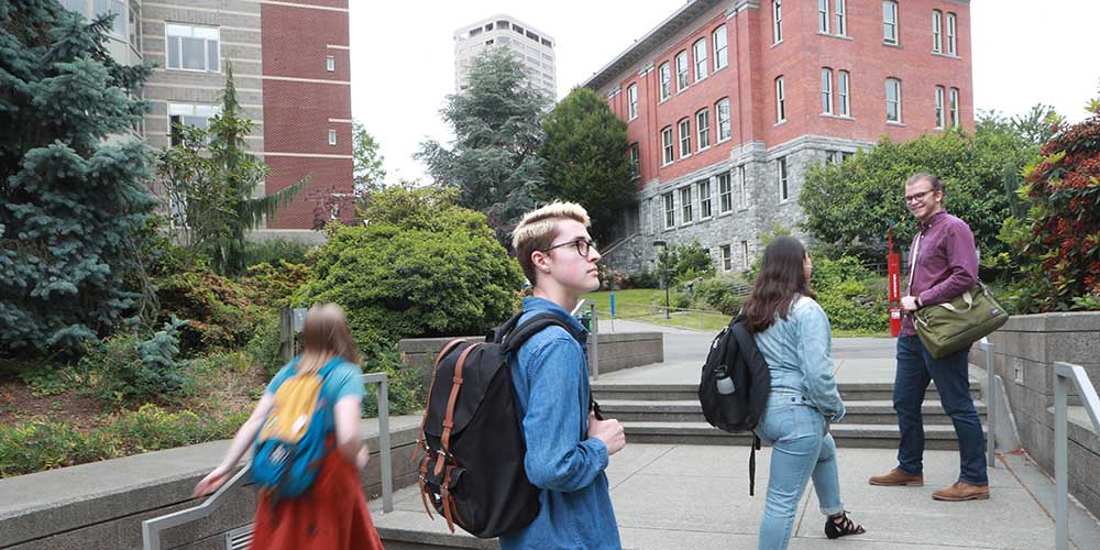   Four students walking through the Quad carrying backpacks