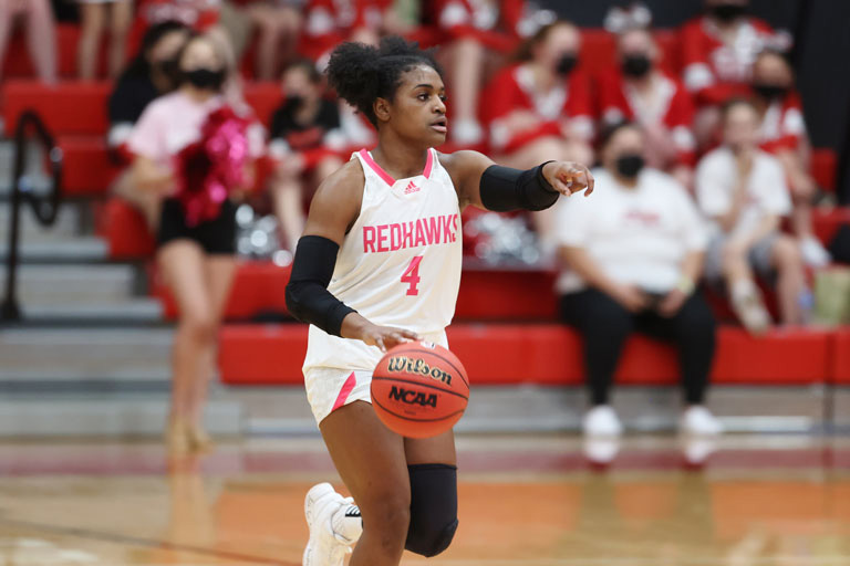   McKenzi Williams, ‘21 dribbling a basketball on the court.